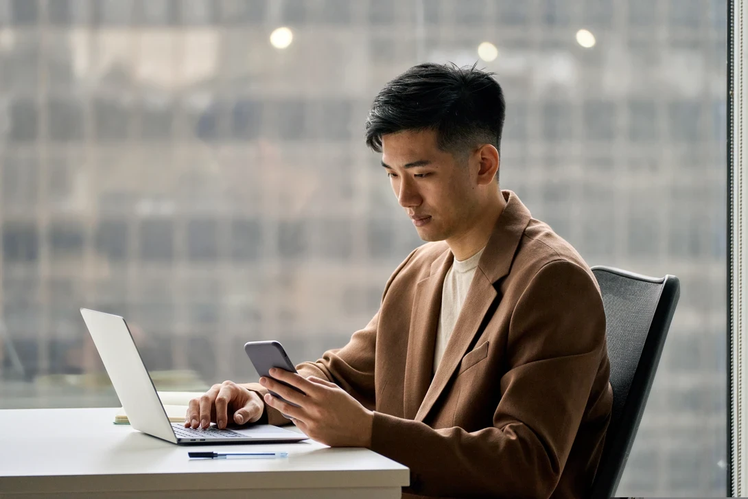 Mobile phone user checking their smart device at their office, in South Korea